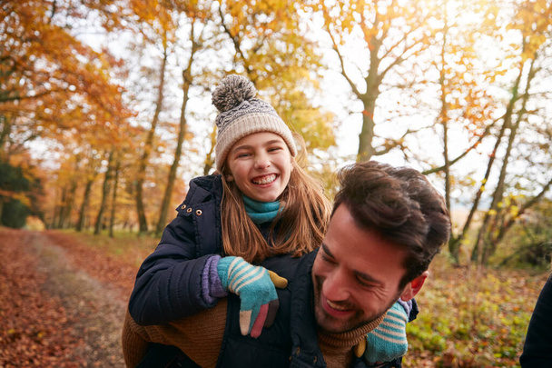 Padre dando risa hija paseo a cuestas en familia paseo a través de otoño bosque - Foto, Imagen