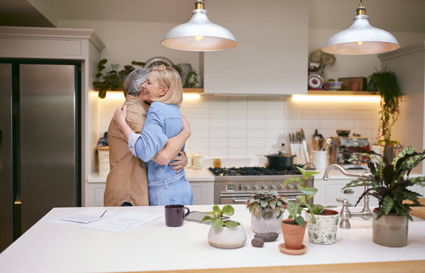 Kochający Dojrzałe para przytulanie jak patrzą na dokumenty finansowe w kuchni w domu - Zdjęcie, obraz