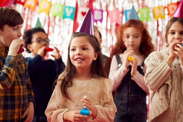 Group Of Children Celebrating At Birthday Party With Paper Hats And Party Blowers - Fotoğraf, Görsel