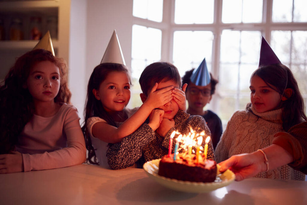 Boy Celebrating Birthday With Group Of Friends At Home Being Given Cake Decorated With Sparkler - Foto, Imagem