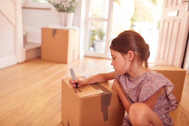 Girl Labelling Boxes Getting Ready For Moving Day Into New Home - 写真・画像