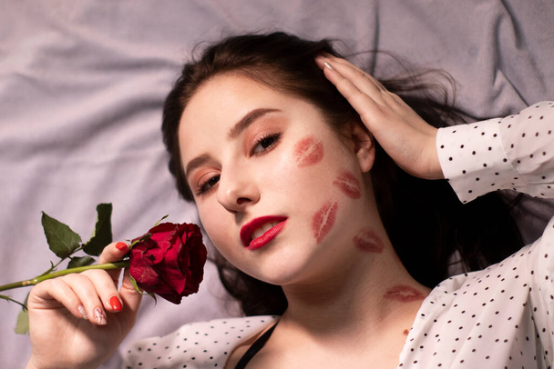 sexy brünette Frau mit Küssen, Lippenstiftspuren auf Gesicht und Hals, mit roter Rose. Freundin, Datum, Wiedereinstieg. Kopierraum - Foto, Bild
