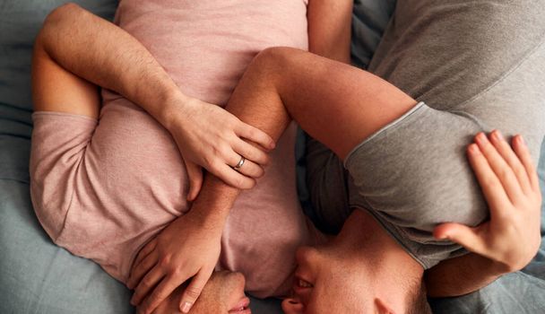 Close Up Overhead Shot Of Loving Same Sex Male Couple Lying On Bed At Home Hugging Together - Foto, afbeelding