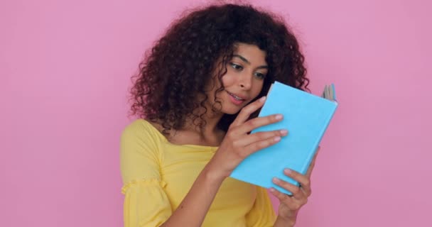 excité jeune femme lecture livre isolé sur rose  - Séquence, vidéo