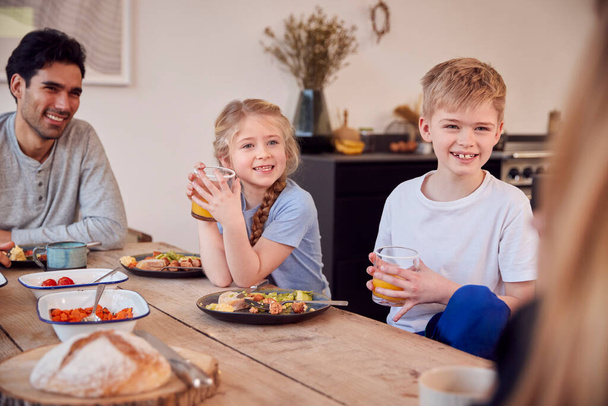 Family Sitting Around Table At Home In Pyjamas Enjoying Brunch Together - Photo, image