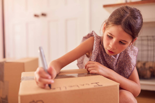 Girl Labelling Boxes Getting Ready For Moving Day Into New Home - 写真・画像