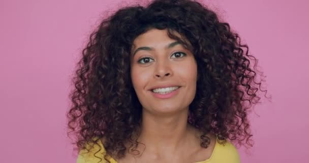 cheerful and curly woman talking while looking at camera isolated on pink - Footage, Video
