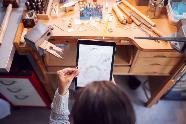 Overhead View Of Female Jeweller Comparing Ring With Drawn Design On Digital Tablet In Studio - 写真・画像
