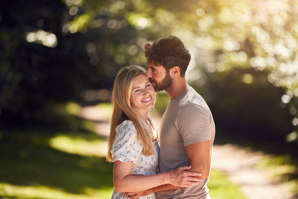 Loving Couple Hugging As They Walk Along Countryside Path In Summer Together - Photo, image