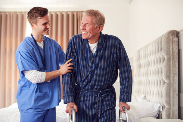 Male Doctor Making Home Visit To Senior Man With Walking Frame For Medical Check In Bedroom - Foto, immagini