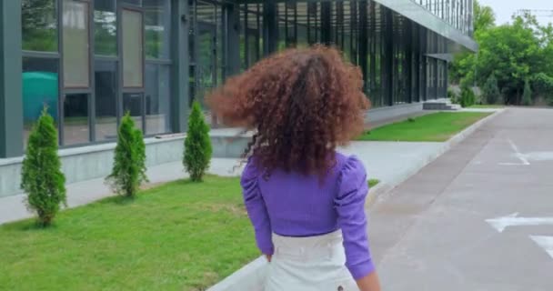 Rückansicht einer lockigen jungen Frau, die nach draußen geht  - Filmmaterial, Video