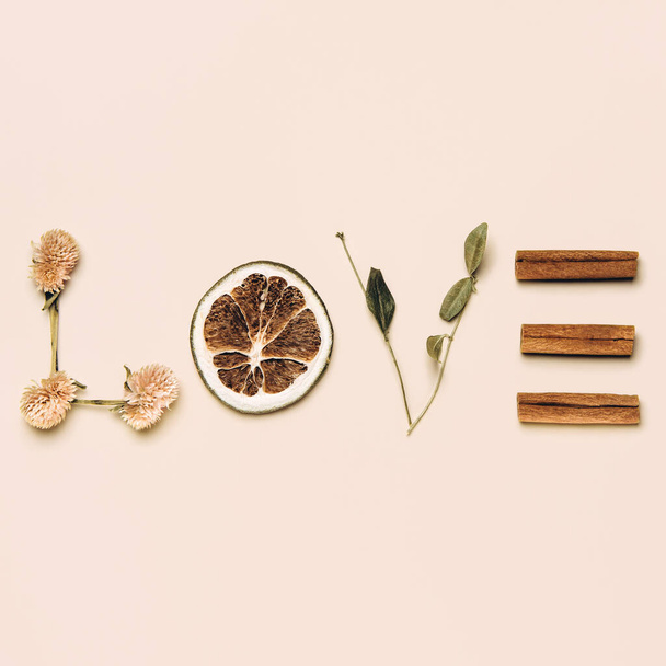 Creative flat lay of word love made with natural leaves, flowers, lenom and cinnamon on pastel background. Love concept.  - 写真・画像