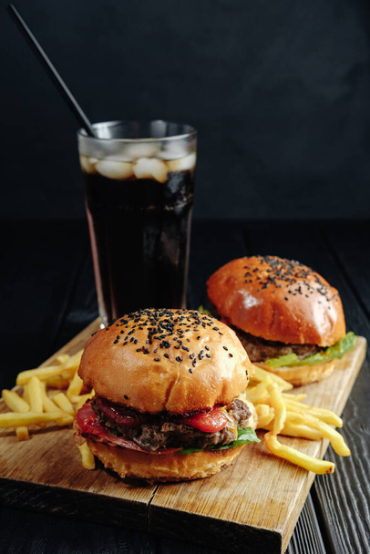 zelfgemaakte sappige hamburger op donker houten plank. Straatvoedsel, fastfood - Foto, afbeelding