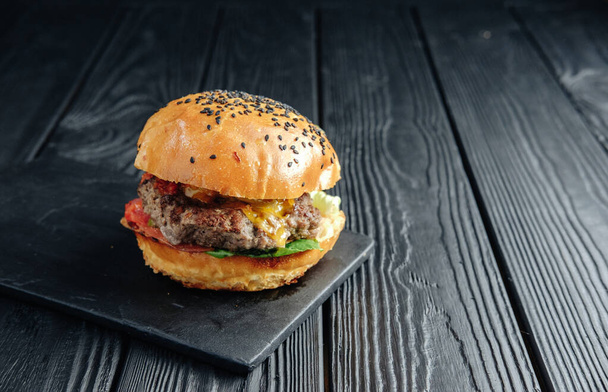 homemade juicy burger on dark wooden board. Street food, fast food - Valokuva, kuva