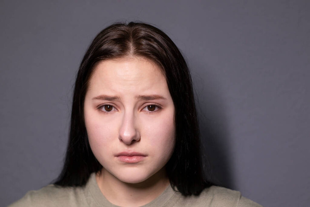 πορτρέτο της γοητευτικής θλιμμένης μελαχρινής γυναίκας σε σκούρο χρώμα t-shirt σε γκρι φόντο τοίχου. Ηθοποιός, συναίσθημα. αντίγραφο χώρου - Φωτογραφία, εικόνα