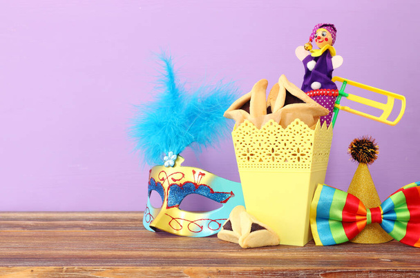 Purim celebration concept (jewish carnival holiday) over wooden table and purple background - Foto, Imagen