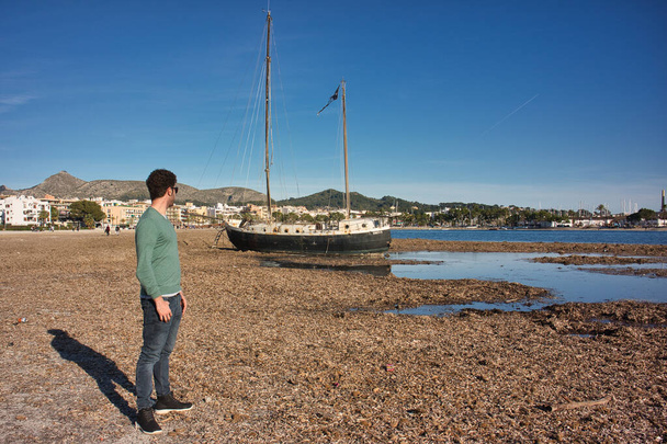 лодка на пляже с человеком сзади - Фото, изображение