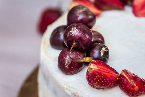Κεράσια και φράουλες με βρώσιμο χρυσό στην κορυφή του cheesecake με καρύδα. - Φωτογραφία, εικόνα