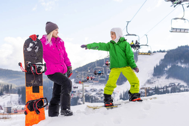Mother and daughter with snowboards are playing in the snow - Photo, Image