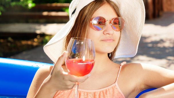 Portret pięknej msiling yougn dziewczyna pije koktajl podczas relaksu w basenie w gorący letni dzień. Pojęcie szczęśliwych wakacji letnich i wakacji - Zdjęcie, obraz