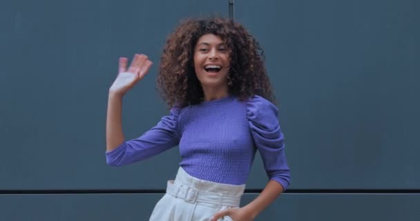 alegre joven mujer saludando mano y posando fuera  - Metraje, vídeo