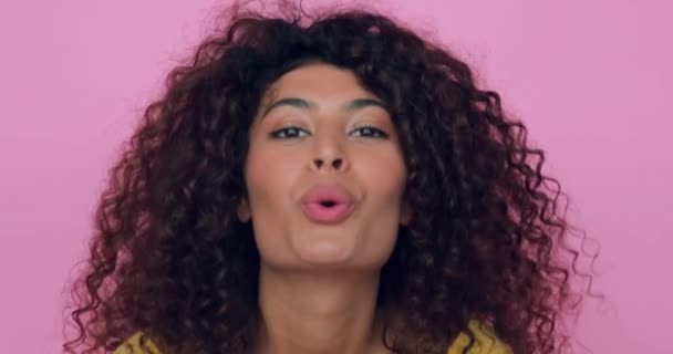 σγουρή νεαρή γυναίκα στέλνει φιλί αέρα απομονωμένο σε ροζ  - Πλάνα, βίντεο