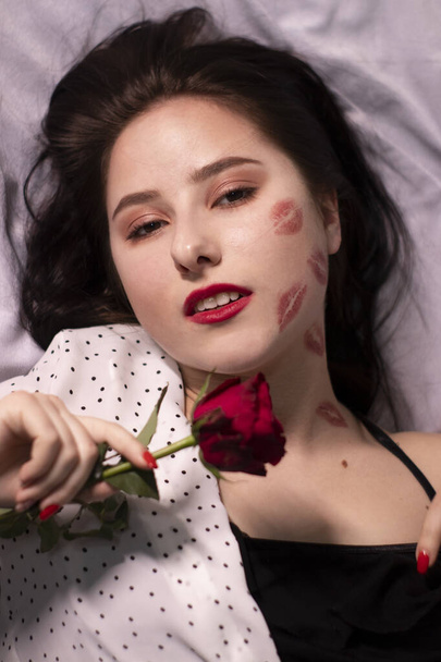 sexy donna bruna con baci, segni di rossetto sul viso e sul collo, con rosa rossa. fidanzata, appuntamento, relazione. copia spazio - Foto, immagini