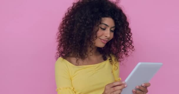 χαρούμενη νεαρή γυναίκα που χρησιμοποιεί ψηφιακό δισκίο απομονωμένο σε ροζ  - Πλάνα, βίντεο
