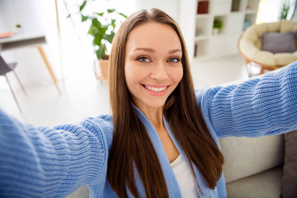 Self-portrait of charming cheerful girl sitting on divan spending free spare time in light flat house apartment living-room indoor - Fotografie, Obrázek