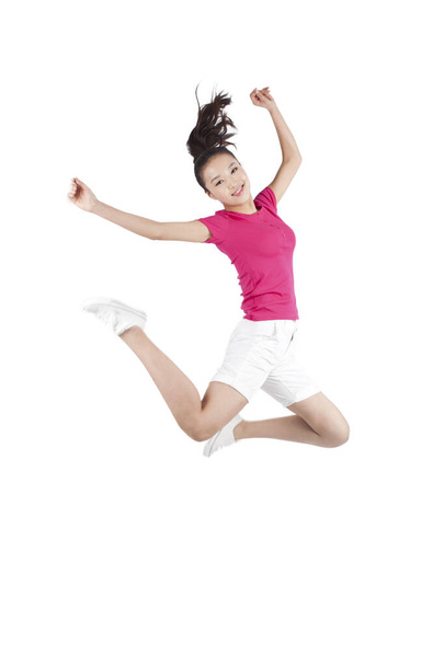 Young woman jumping in air with arms outstretched  - Foto, afbeelding