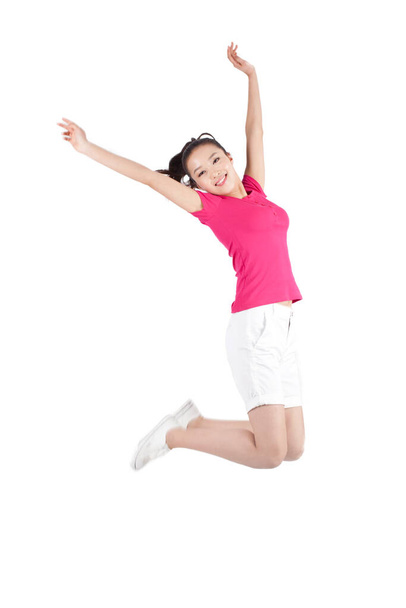 Young woman jumping in air with arms outstretched - 写真・画像