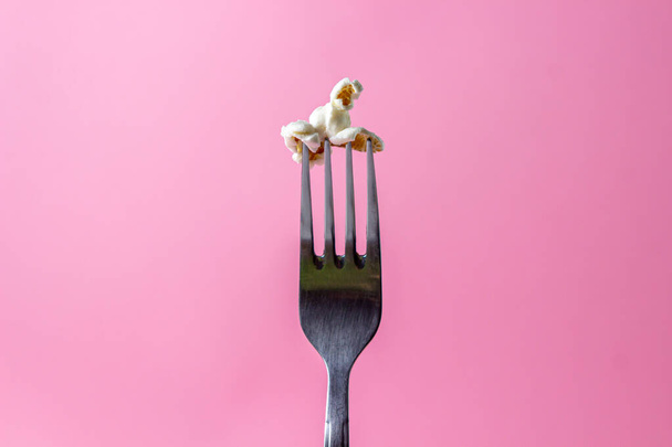 Popcorn on a pink background. One popcorn on a fork. Movie snack - Photo, Image