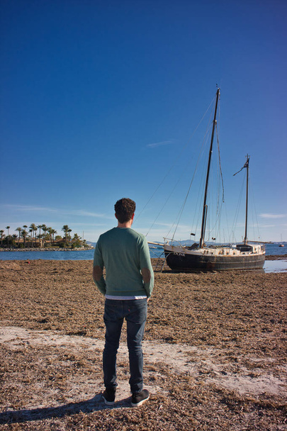 лодка на пляже с человеком сзади - Фото, изображение