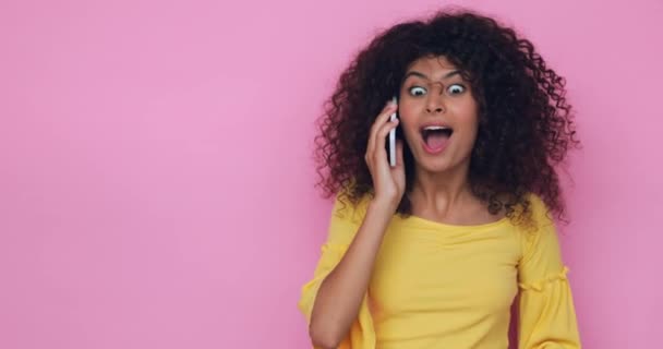 jovem mulher espantada falando no smartphone isolado em rosa - Filmagem, Vídeo