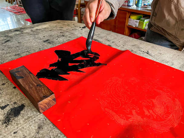 Een kalligraaf is het creëren en schrijven van lente festival coupletten, Chinees Nieuwjaar Lente Festival. Vertaling: De lente is in veel steden. - Foto, afbeelding