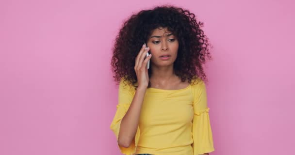 Frustrierte junge Frau spricht auf Smartphone isoliert auf rosa - Filmmaterial, Video