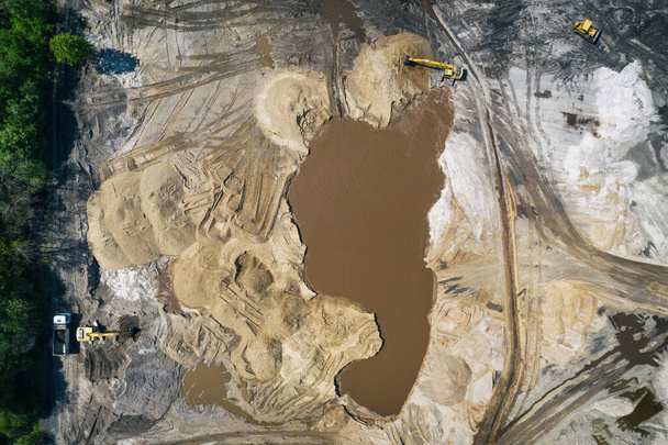 Keltainen kaivinkone toimii. Kaivinkone kaivaa hiekkaa, maa vedestä. Teollisuuden antenni drone valokuva näkymä - Valokuva, kuva