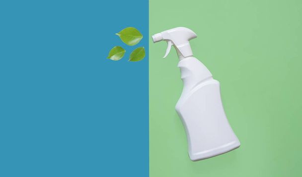 Spray bottle with leaves for cleaning various surfaces in the kitchen, bathroom and other areas on a green and blue background. Ecological cleaning concept. Early spring regular cleaning. top view - Foto, Imagem