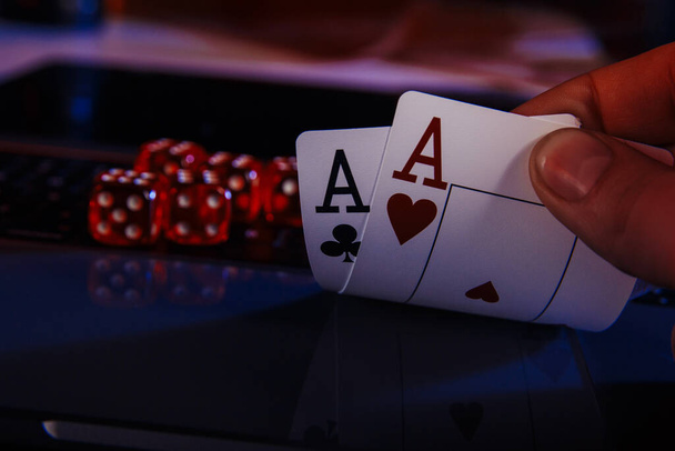 Kostky a karty pro poker v ruce na notebooku, online kasino koncept - Fotografie, Obrázek