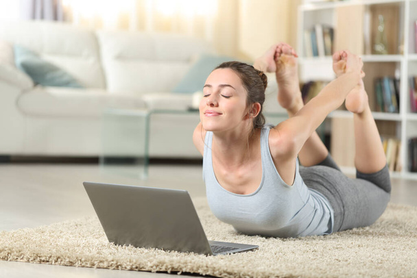 Satisfied woman e-learning yoga exercise using a laptop at home - Φωτογραφία, εικόνα