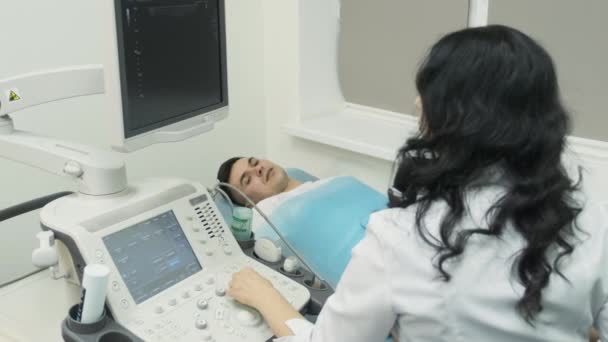 Donna medico esamina paziente giovane uomo in dispositivo a ultrasuoni, sonografia. - Filmati, video