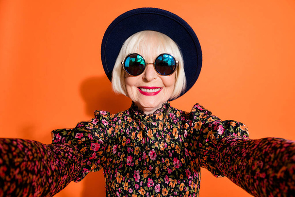 Portrait of happy smiling cheerful positive grandmother take selfie wear sunglasses isolated on orange color background - Photo, image