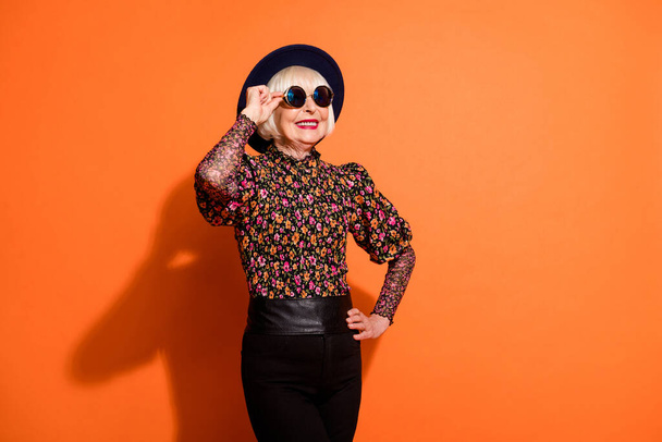 Photo of good mood happy smiling positive old woman look copyspace wear sunglasses isolated on orange color background - Valokuva, kuva