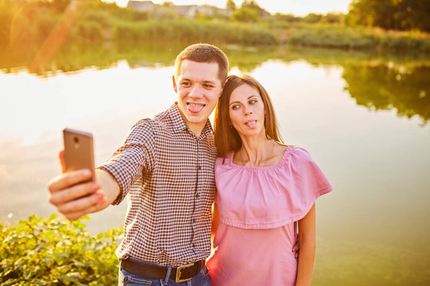Couple taking photo of themselves with smart phone on romantic picnic date - Foto, afbeelding
