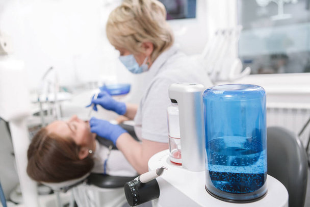 Selective focus on modern dental treatment device, professional dentist working with patient on background - Foto, Imagen