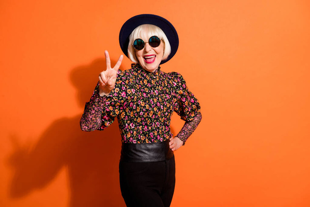 Photo of smiling cheerful good mood positive grandmother showing v-sign isolated on orange color background - Φωτογραφία, εικόνα