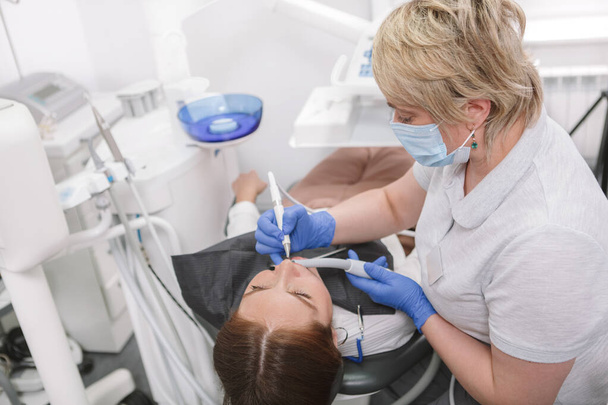 Mature female dentist treating teeth of female patient - Фото, зображення