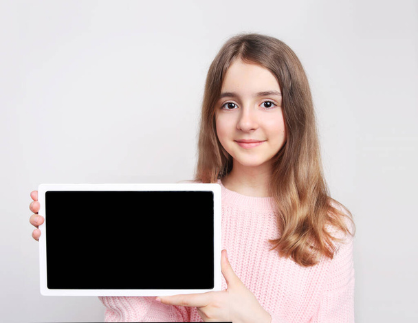 Caucasian child girl holding tablet,empty space blank promotional design image.Kid with screen closeup.Female person advertising product. - Φωτογραφία, εικόνα