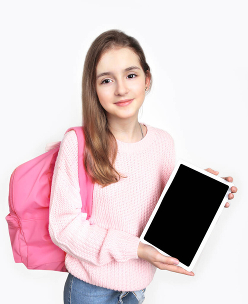 Caucasian child girl with tablet on white background.Young girl teen age showing empty screen. Advertisement blank.Female person promote product.Pupil with backpack. - Fotó, kép