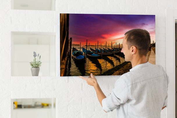 man holds photo canvas at home - Foto, Bild